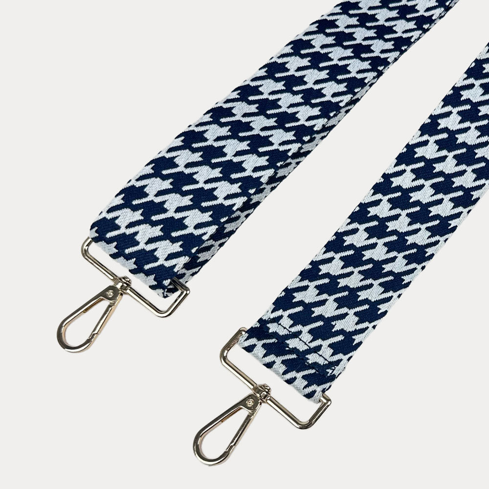 Navy and white houndstooth patterned strap with gold metal clasps on a light gray background