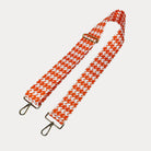 Orange and white houndstooth patterned strap with gold metal clasps on a light gray background