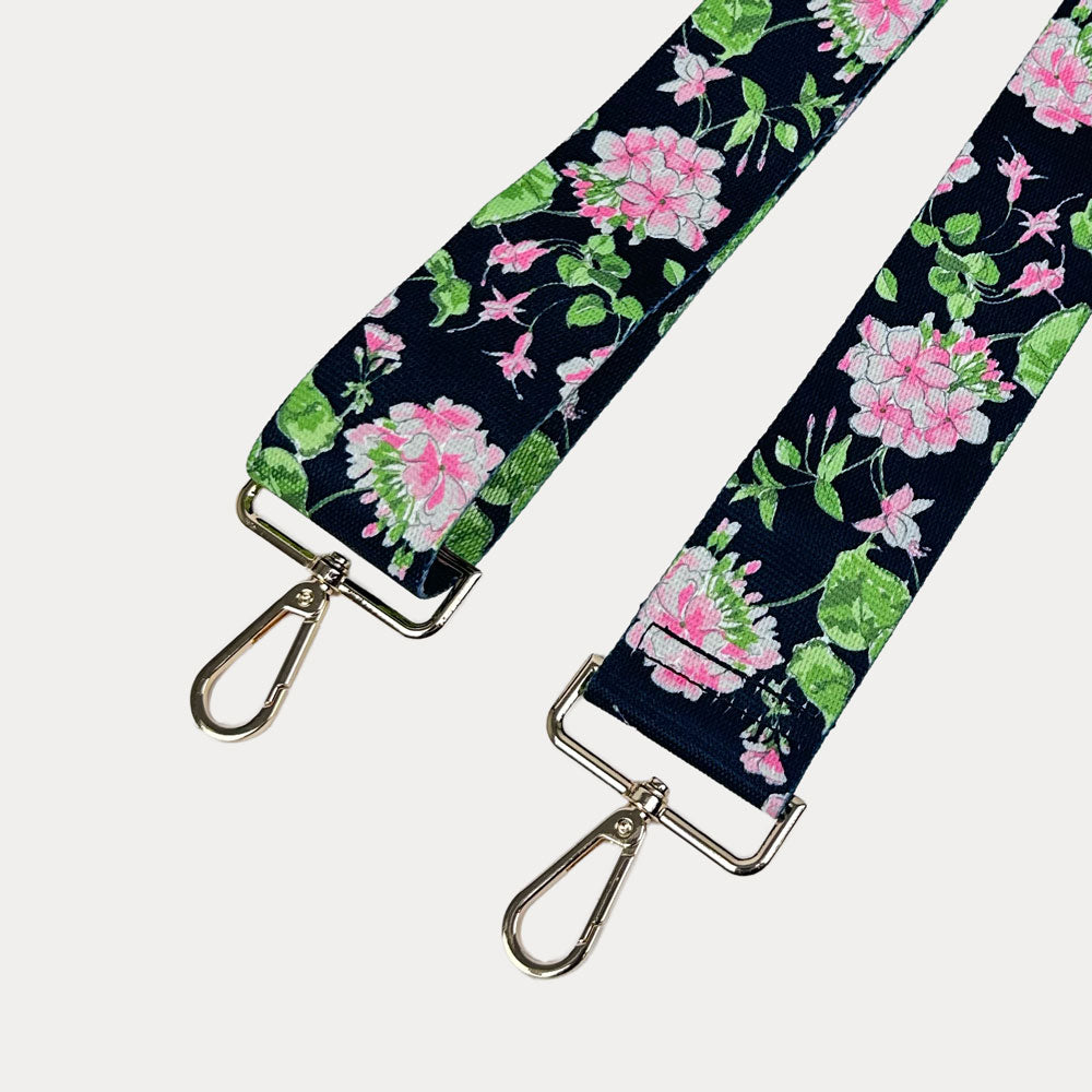 Black ground floral patterned strap with gold hardware on a light gray background