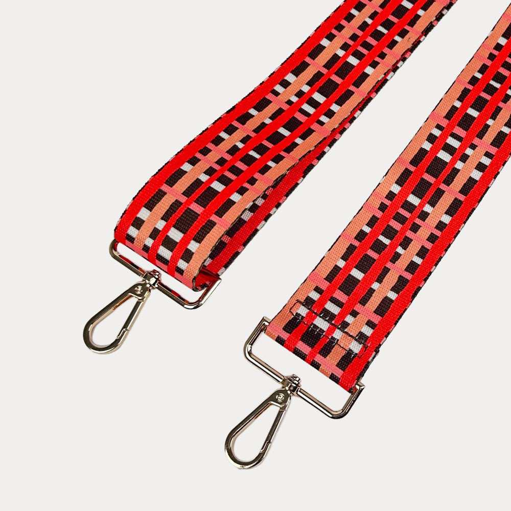 Brown, red and peach plaid strap with gold metal hardware on a white background