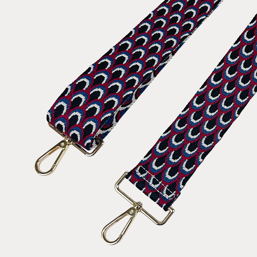 Black, Burgundy, and blue patterned bag strap with gold hardware on a light gray background