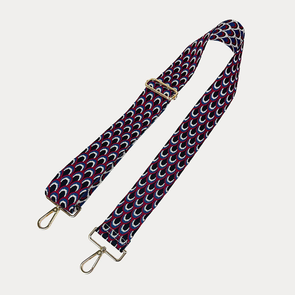 Black, Burgundy, and blue patterned bag strap with gold hardware on a light gray background