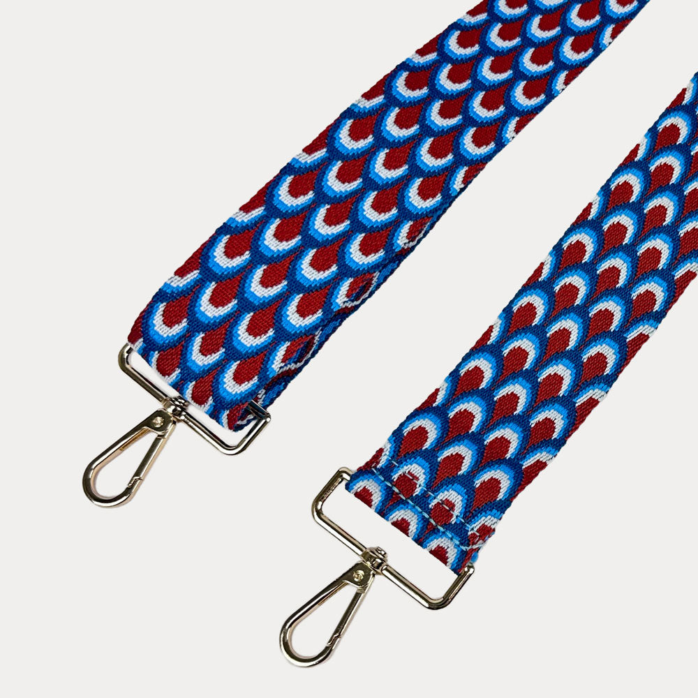 Blue, Red, White patterned bag strap with gold hardware on a light gray background