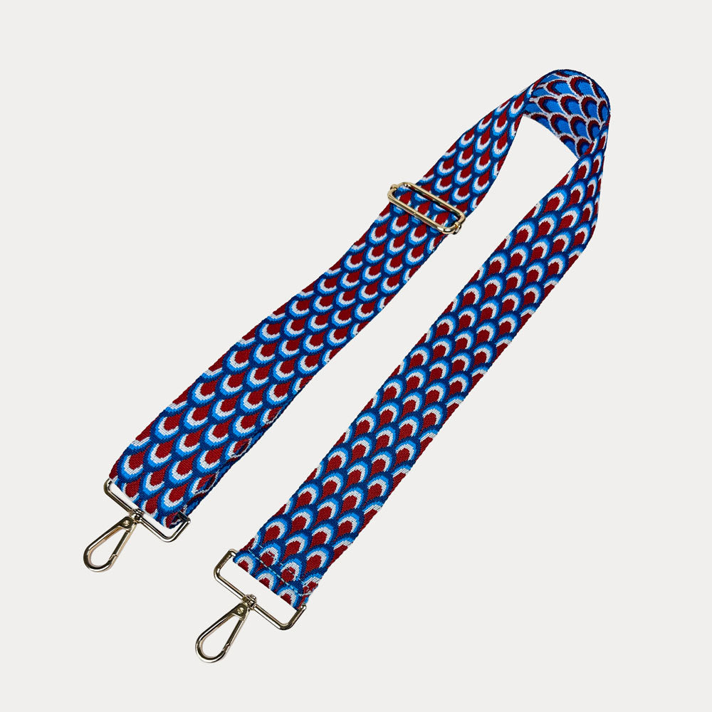 Blue, Red, White patterned bag strap with gold hardware on a light gray background