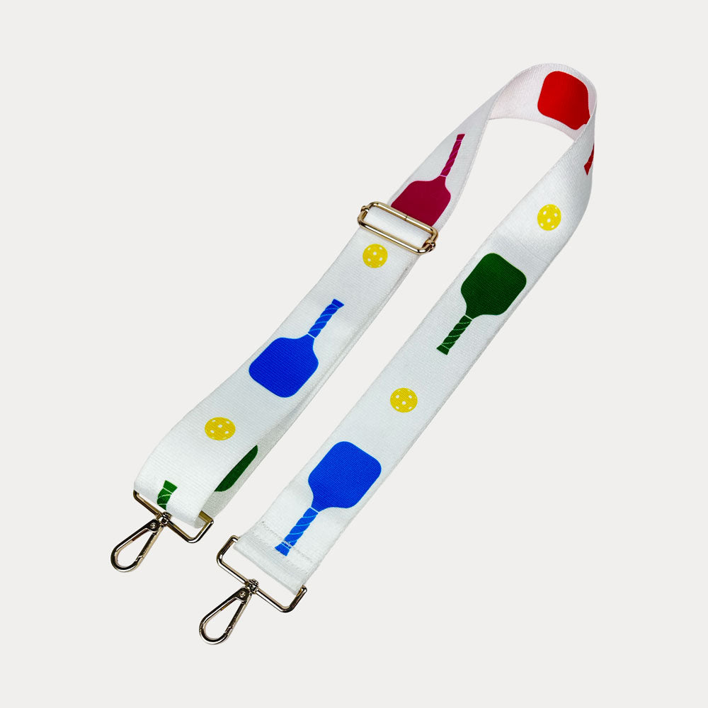 White ground with colorful pickleball paddles and white pickleball graphics with gold hardware bag strap
