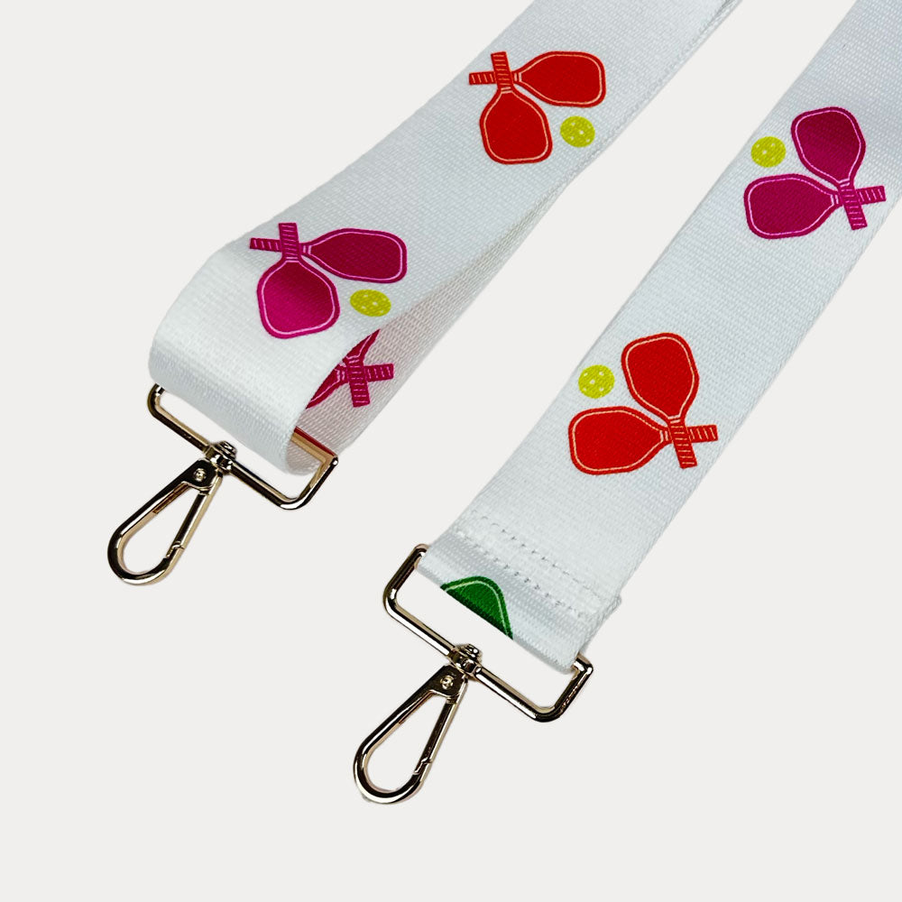 White ground with colorful pickleball paddle graphics with gold hardware bag strap