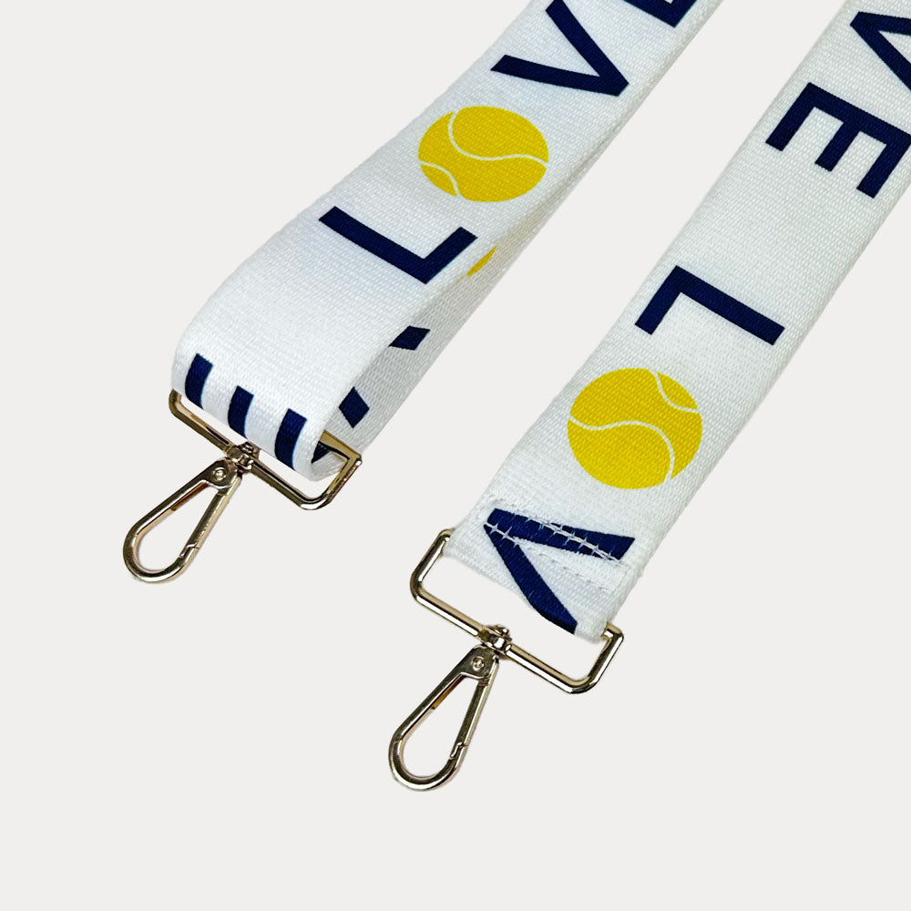 White ground with 'LOVE' text and tennis ball graphics with gold hardware bag strap