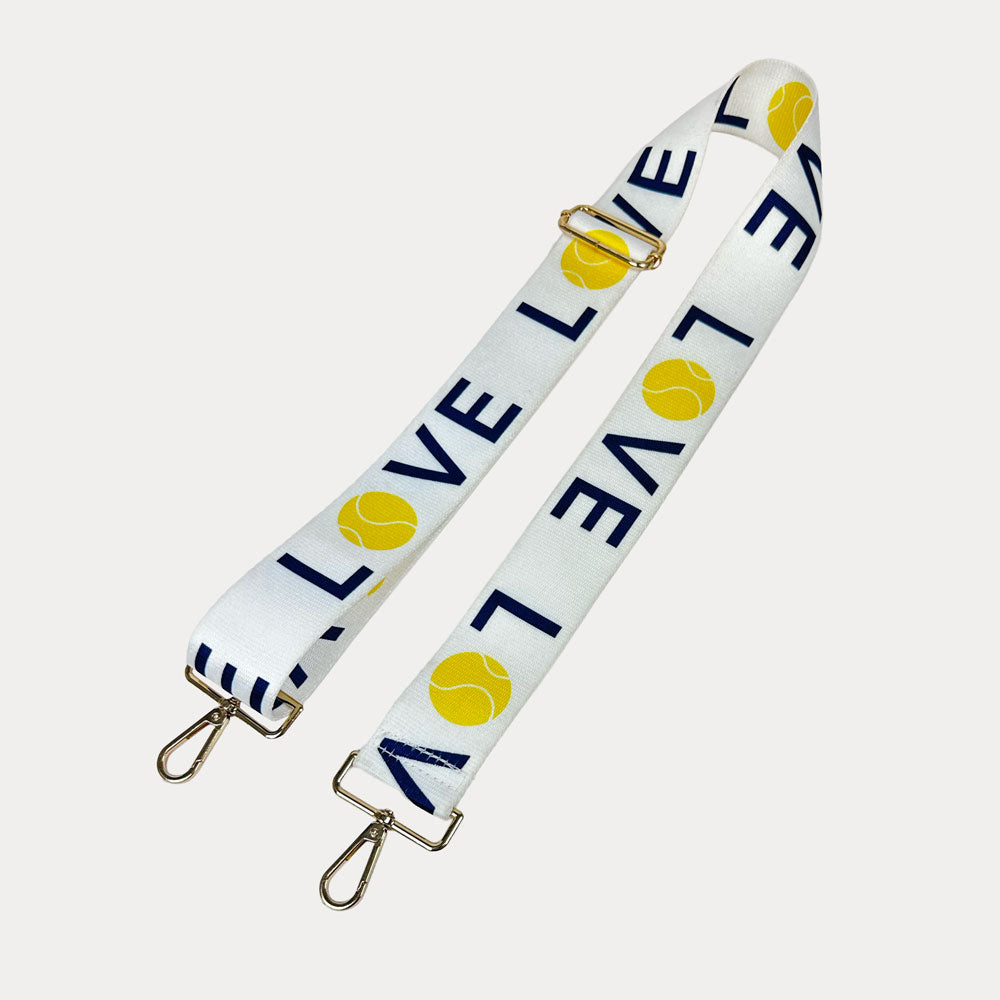 White ground with 'LOVE' text and tennis ball graphics with gold hardware bag strap