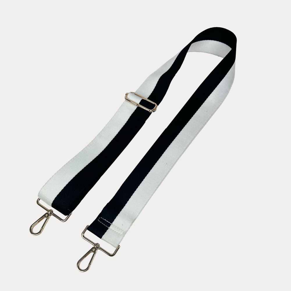 Black and White striped bag strap with gold hardware on a light gray background