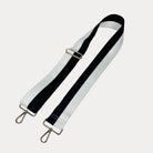 Black and White striped bag strap with gold hardware on a light gray background