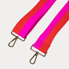 Pink and orange striped bag strap with gold hardware on a light gray background