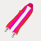 Pink and orange striped bag strap with gold hardware on a light gray background