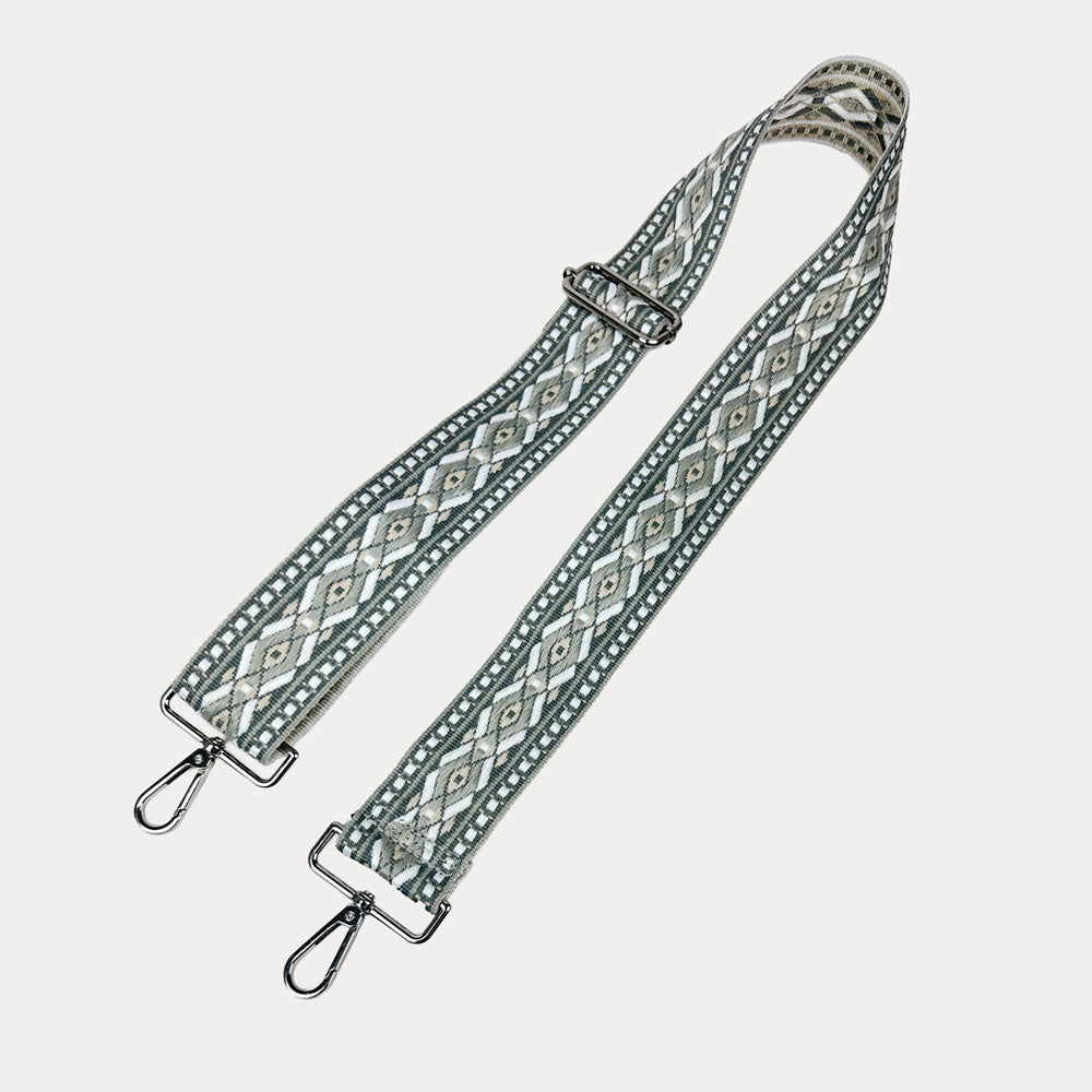 Grey, white, tan diamond patterned bag strap with silver metal clasps on a light gray background