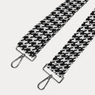 Black and white houndstooth patterned strap with silver metal clasps on a light gray background