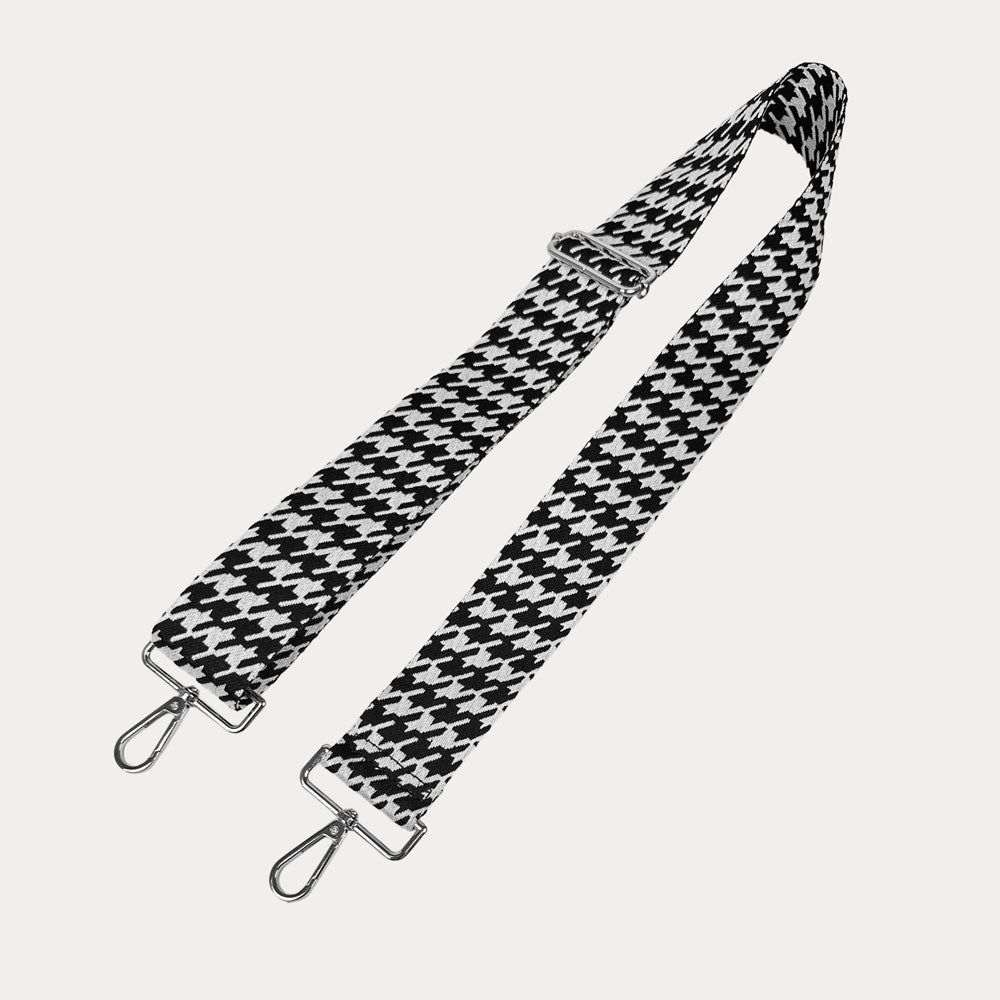 Black and white houndstooth patterned strap with silver metal clasps on a light gray background