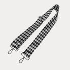 Black and white houndstooth patterned strap with silver metal clasps on a light gray background