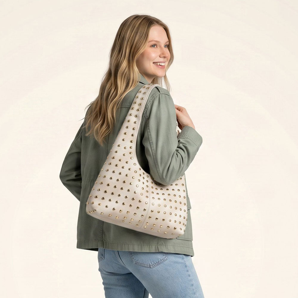 Woman wearing a cream suede hobo with gold studs