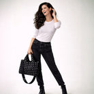 Woman holding a black studded tote against a white background