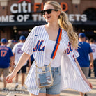 Woman outside a baseball game, wearing a clear messenger bag with a striped bag strap.