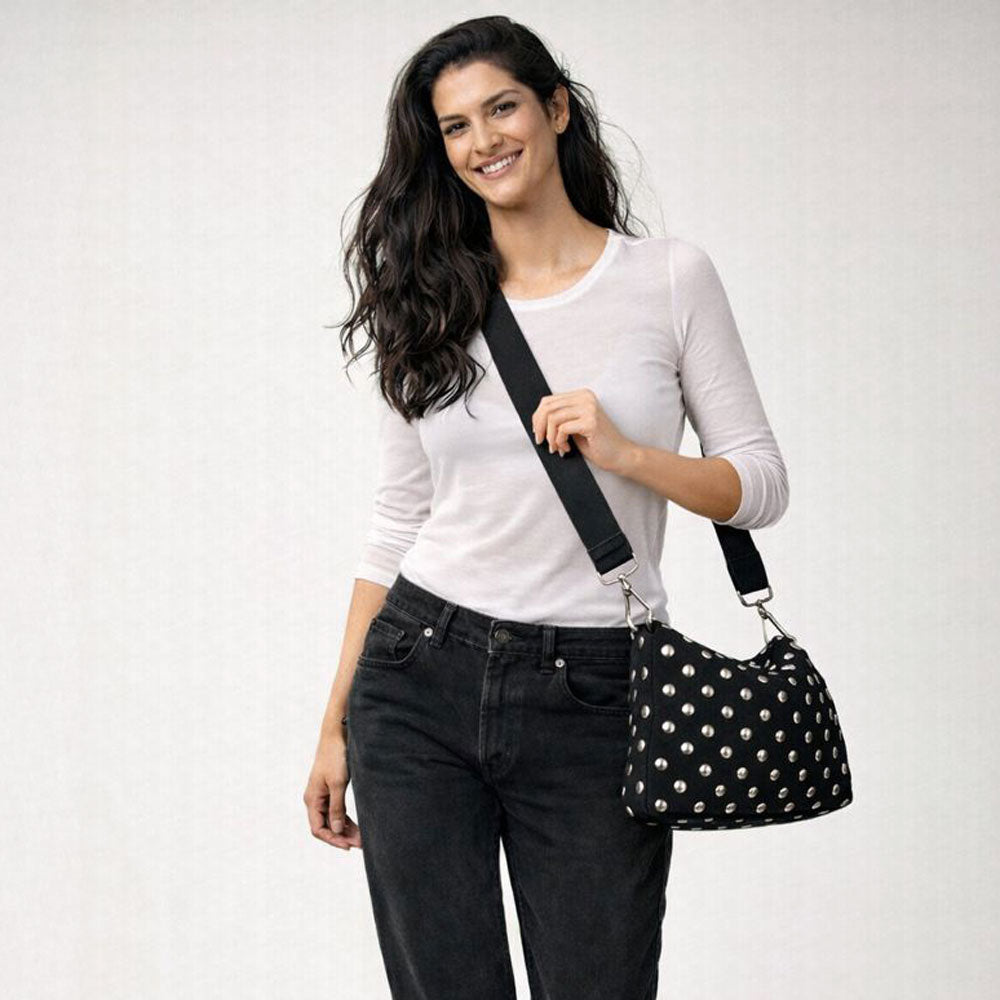 Woman wearing a black silver studded crossbody handbag against a white background