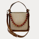 Raffia handbag with Camel Vegan Leather Details and  a beaded strap on a light gray background