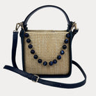 Woven handbag with navy bead embellishments on a light gray background