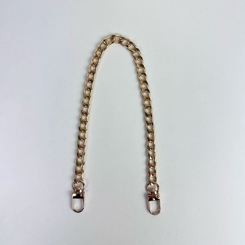 A gold chain short strap with gold hardware on a light grey background. 