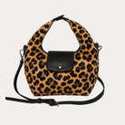 Handbag with leopard print vegan suede and black leather accents on a light gray background