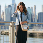 Woman holding a raffia handbag with a city skyline in the background