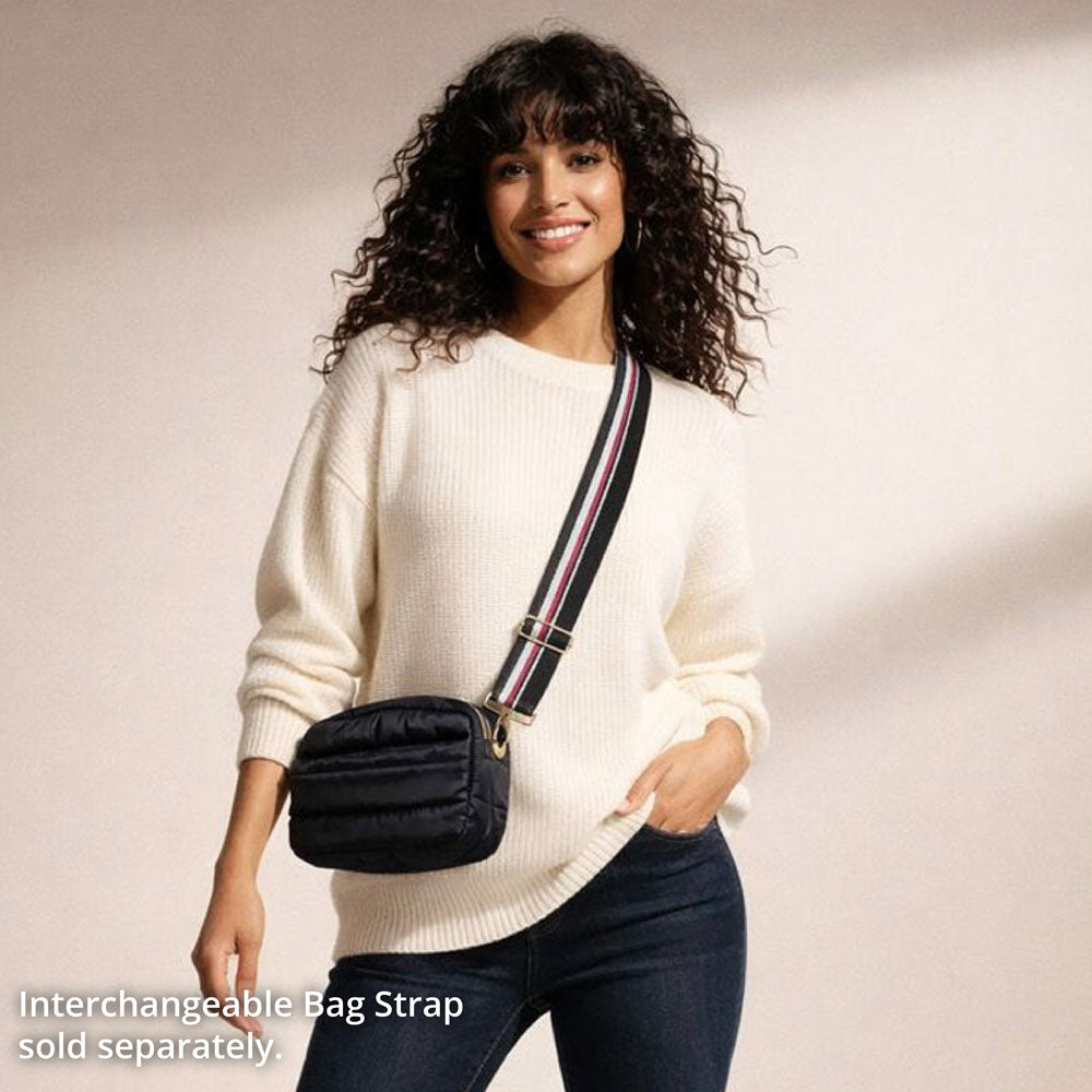 Woman wearing a white sweater with a black bag featuring an interchangeable strap.