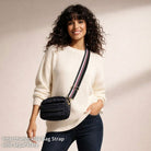 Woman wearing a white sweater with a black bag featuring an interchangeable strap.