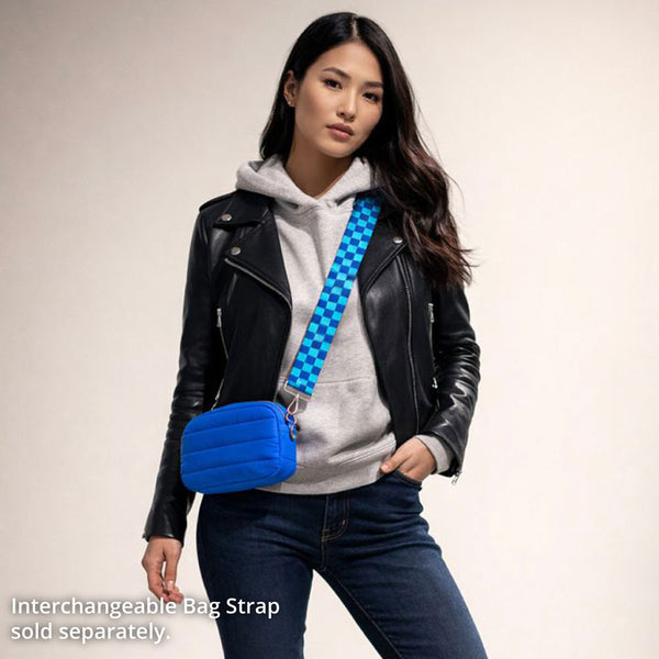 Woman wearing a black leather jacket, gray hoodie, and blue jeans with a blue crossbody bag on a beige background