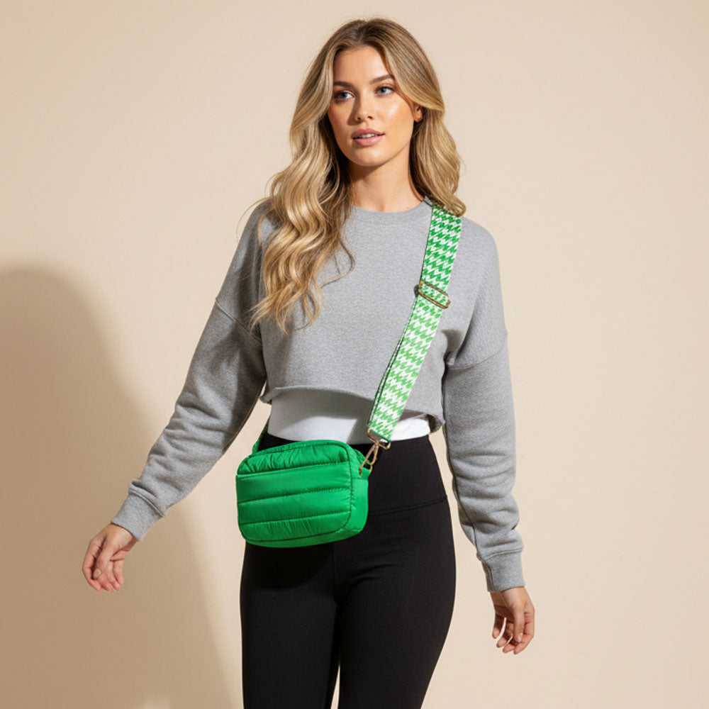 Woman wearing a green puffer bag with a checkered strap on a beige background