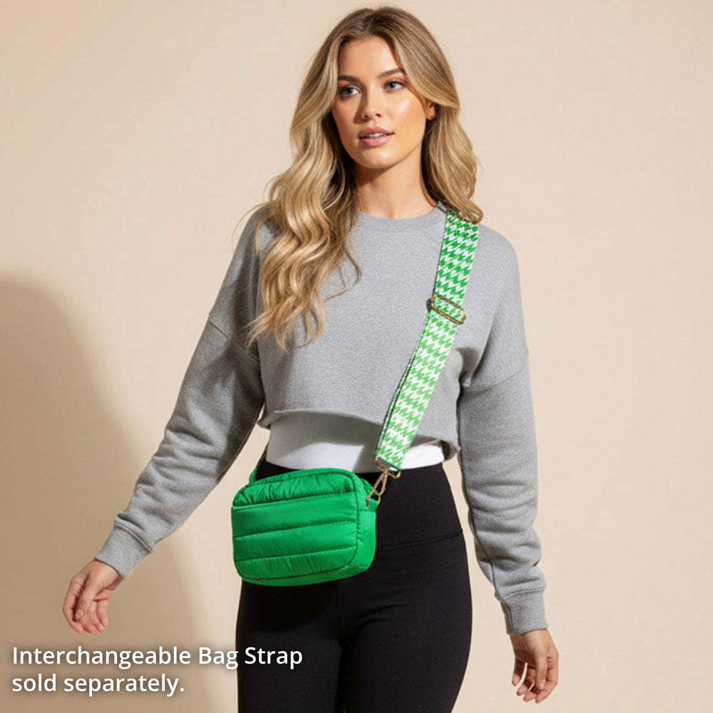 Woman wearing a green puffer bag with a houndstooth strap on a beige background