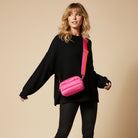 Woman wearing a black outfit with a pink bag on a beige background