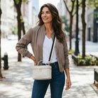 Woman walking on a city street wearing a cream handbag