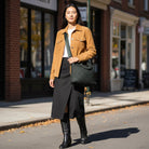 Woman in the city, walking with a army green tote across her body with a crossbody bag strap. 