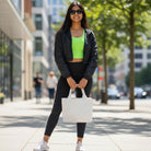 Woman in athletic wear holding a white tote on a city street