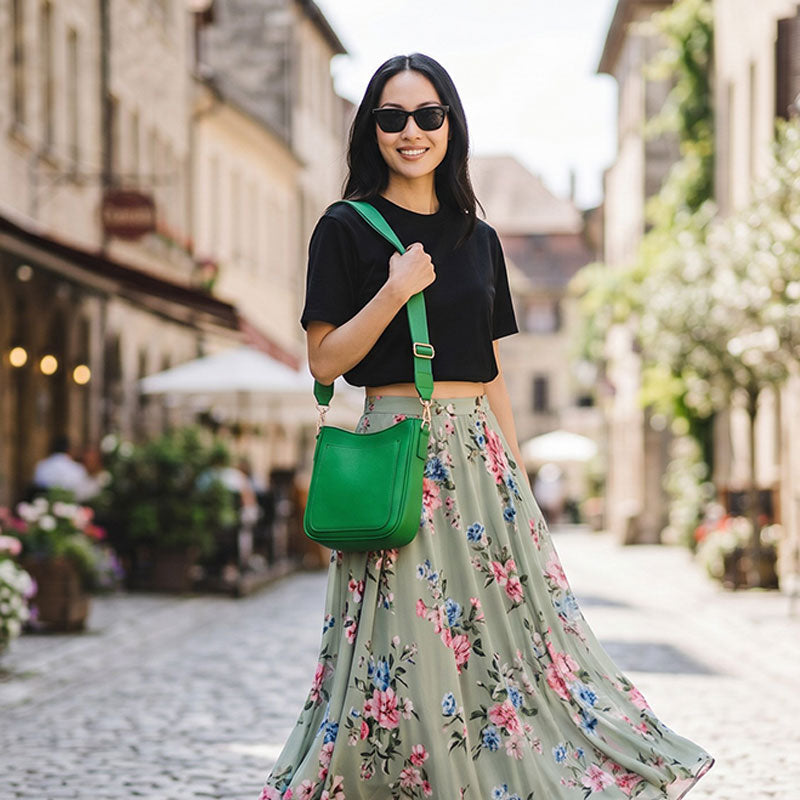 Woman wearing a green bag on a street with buildings and flowers in the background