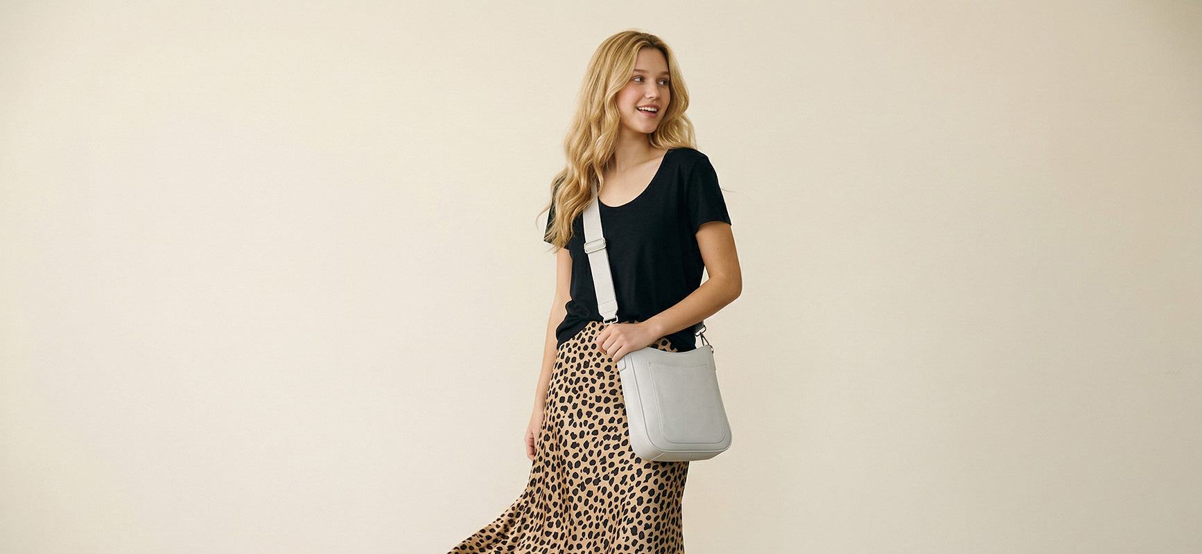 Woman wearing  a cream handbag against a beige background