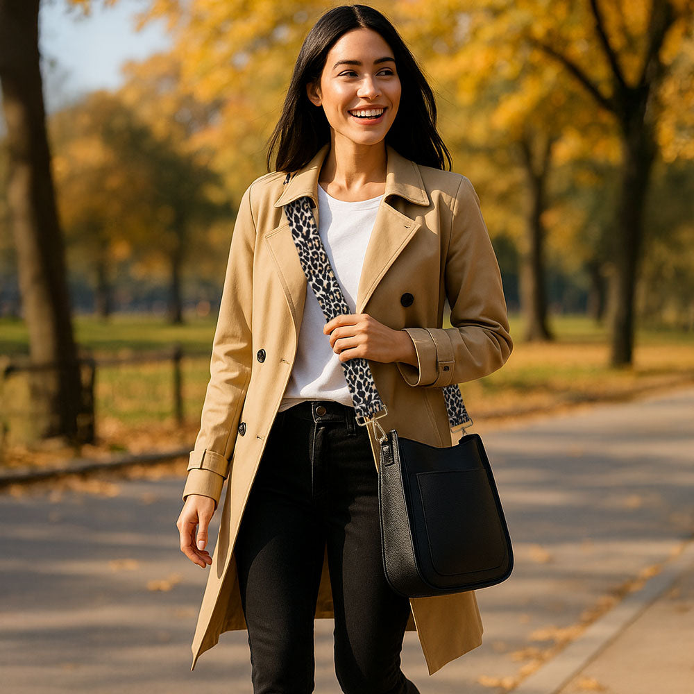 Woman walking in the park wearing a black crossbody bag with a animal print bag strap