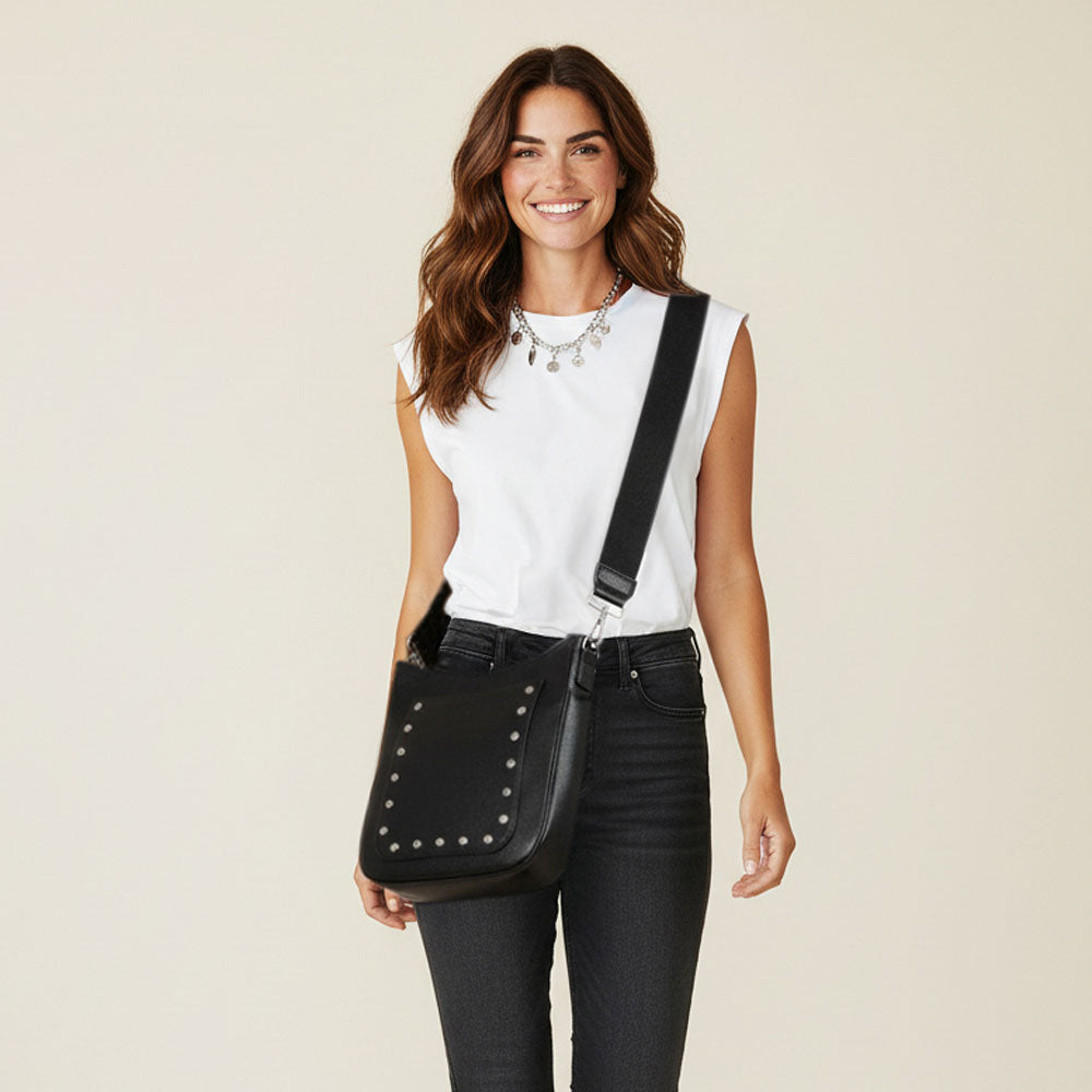 Woman holding a black studded bag against a beige background