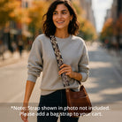 Woman posing on city side walk wearing a brown crossbody bag and printed animal bag strap