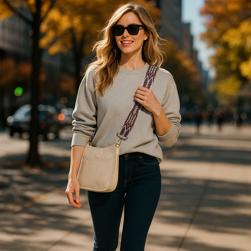 Woman walking in the park, wearing a cream crossbody bag with a patterned embroidered bag strap