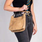 Person holding a brown leather handbag against a gray background