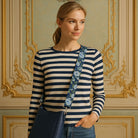 Woman posing in a room with victorian wallpaper, wearing a navy bag with the printed floral bag strap