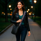 Woman walking in the early evening, wearing a black crossbody bag and metallic striped bag strap. 