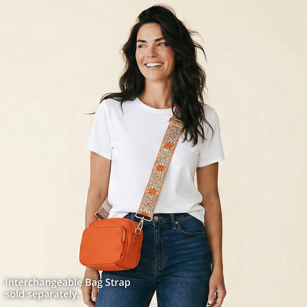 Woman wearing an orange bag with a decorative strap on a beige background