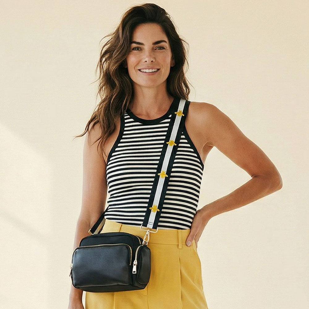 Woman wearing a striped top and yellow pants with a black handbag on a beige background