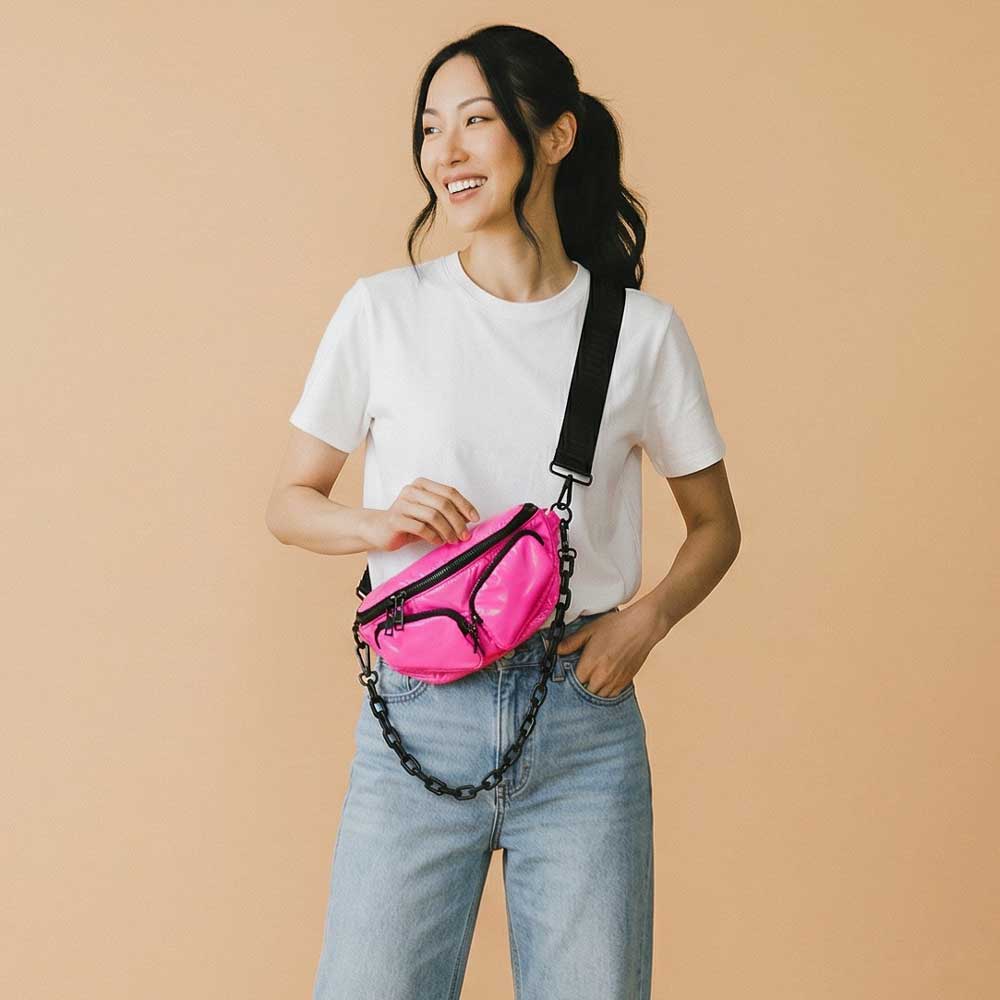 Woman wearing a pink sling bag with a black chain on a beige background